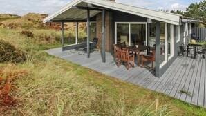 A modern house with a covered patio, a brick fireplace, and a dining area with outdoor furniture. - "Elsa" - 700m from the sea by Interhome (Oksbøl)