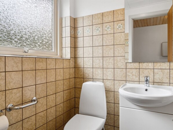 A bathroom with a toilet, sink, and hand dryer.