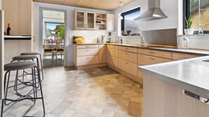 Una cocina moderna con armarios de madera, una isla grande y vistas al exterior.