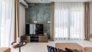 A modern living room with a flat-screen TV, a wooden entertainment unit, and a sofa with patterned cushions. - Modern Villa Callista - 3 bedroom luxury villa (Žrnovnica)