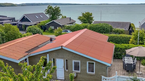 A single-story house with a red roof, a front door, and a small patio area with outdoor furniture. - "Eilke" - 50m from the sea by Interhome (Rønde)