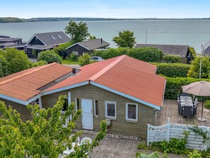 Ein Wohngebiet mit Häusern, einer Terrasse mit Gartenmöbeln und Blick auf das Wasser.