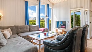A modern living room with a sectional sofa, a leather armchair, a glass coffee table, and a flat-screen TV. - "Eilke" - 50m from the sea by Interhome (Rønde)