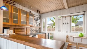 A kitchen with wooden cabinets, a wooden countertop, and a window with a view of the outside. - "Eilke" - 50m from the sea by Interhome (Rønde)