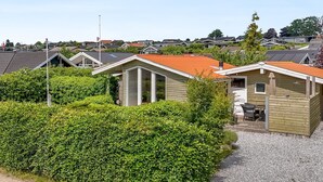 A row of small, single-story cabins with red roofs, surrounded by dense green hedges, set in a residential area. - "Eilke" - 50m from the sea by Interhome (Rønde)