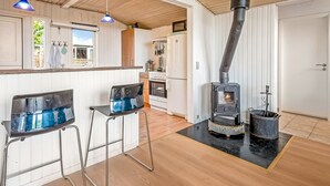 A modern kitchen with a wood-burning stove, white cabinetry, and a bar area with stools. - "Eilke" - 50m from the sea by Interhome (Rønde)