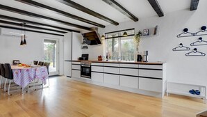 A modern kitchen with white cabinets, a wooden countertop, and a dining area with a table set for four.