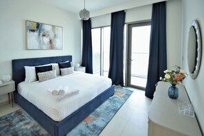 Ein modernes Hotelzimmer mit einem großen Bett, einem Nachttisch, einer Kommode, einer Vase mit Blumen und einem großen Fenster mit Vorhängen.