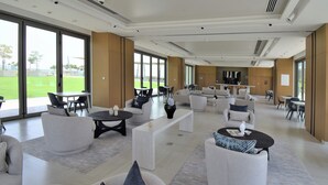 Un espace de détente spacieux et moderne, doté de sièges confortables, de grandes fenêtres et offrant une vue sur l’extérieur.