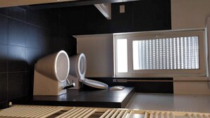 A modern bathroom with a toilet, bidet, and a window with blinds. - Modern and spacious apartment between sea and mountain (Val Vomano)