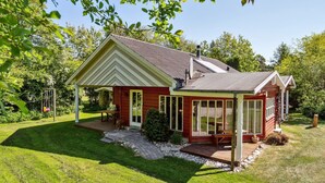 Ein rotes Haus mit überdachter Veranda und Wintergarten.