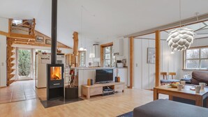 Ein geräumiges Wohnzimmer mit Kamin, Holzboden, Fernseher und Essbereich mit Tisch und Stühlen.
