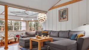 Ein modernes Wohnzimmer mit einem grauen Ecksofa, einem Holztisch und einem gemusterten Teppich.
