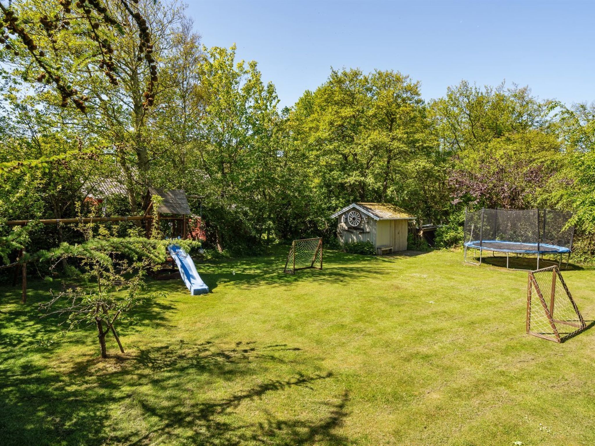 A backyard with a trampoline, a small shed, and a slide.