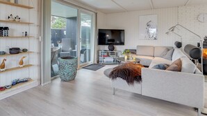 Un salon moderne avec un canapé gris, un téléviseur et une cheminée.