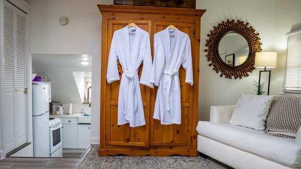 A room with a wooden wardrobe, a white sofa, and a patterned rug.
