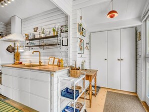 A kitchen with white cabinetry, a wooden island, a hanging light fixture, and a door with a handle.