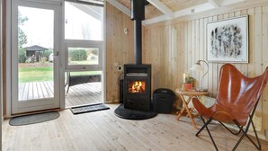 A cozy room with a wood-burning stove, a sliding glass door leading to a deck, and a framed artwork on the wall.