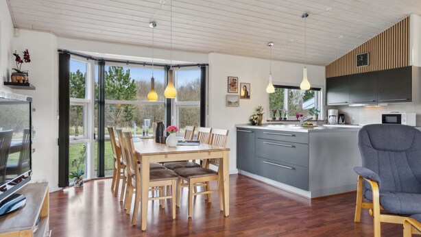 A modern kitchen with grey cabinets, a wooden dining table, and a grey chair. - "Andrea" - 1.4km from the sea by Interhome (Hals)