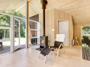 En mysig stuga med en vedeldad kamin, en bekväm fåtölj och en matplats.