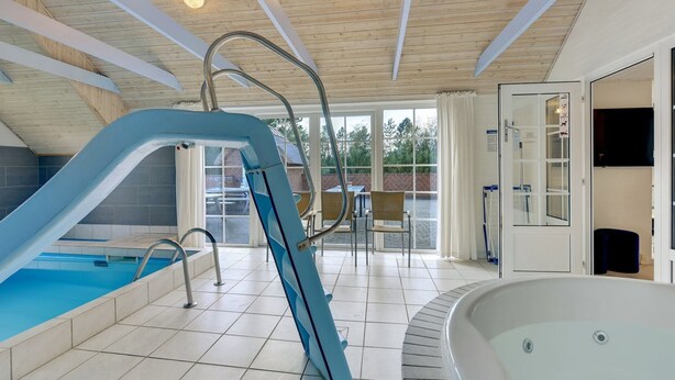 An indoor swimming pool with a blue slide, a hot tub, and a sunlit room with a view of the outdoors. - "Jorkin" - 1.8km from the sea by Interhome (Ulfborg)