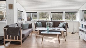 Un salon spacieux avec une grande fenêtre, un canapé, une table basse et un meuble.