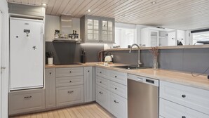 Une cuisine moderne avec des meubles blancs, un lave-vaisselle en acier inoxydable et un plan de travail en bois.