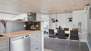 Une cuisine moderne équipée d’un lave-vaisselle, d’une machine à café et d’un coin repas avec une table et des chaises.