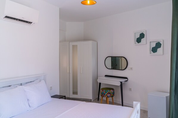 A bedroom with a bed, a wardrobe, a desk with a mirror, and a small stool. - Mea Reisdere (Cesme)