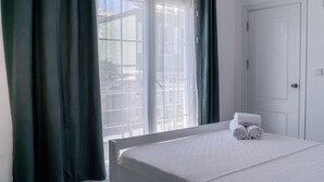 A hotel room with a bed, a window with curtains, and a door. - Mea Reisdere (Cesme)
