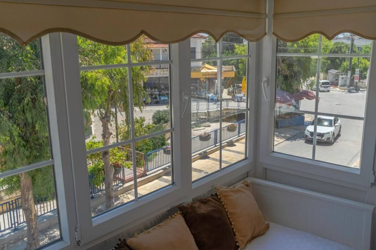 A room with a large window overlooking a street and greenery.