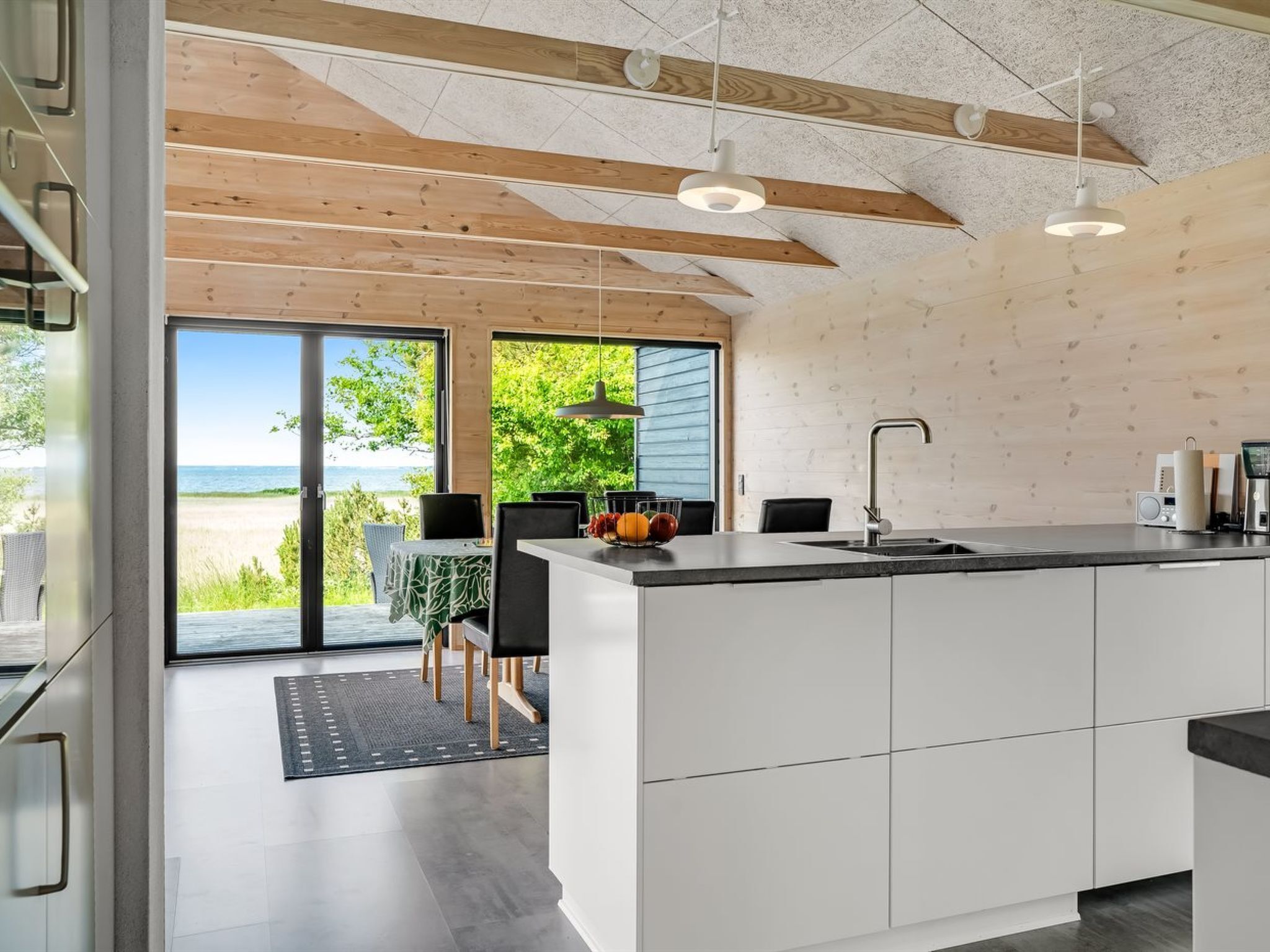 A modern kitchen with a large island, a dining area with a view of the beach, and a spacious living area with a sliding glass door.