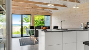 A modern kitchen with a large island, a dining area with a view of the beach, and a spacious living area with a sliding glass door.