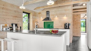 A modern kitchen with wooden walls, a central island, and pendant lighting.