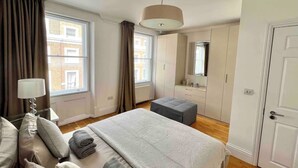 A bedroom with a bed, bedside table, lamp, and a window with curtains.