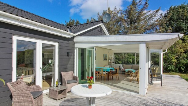 Un patio techado con mobiliario exterior, una zona de comedor y vista al interior de la casa.