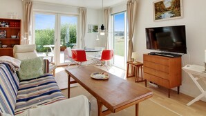 Una sala de estar moderna con un sofá, una mesa de comedor, un televisor y una estantería.