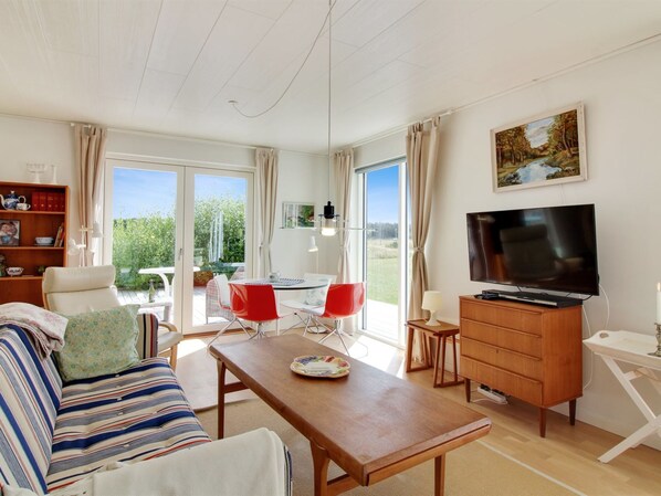 A modern living room with a sofa, a dining table, a TV, and a bookshelf.