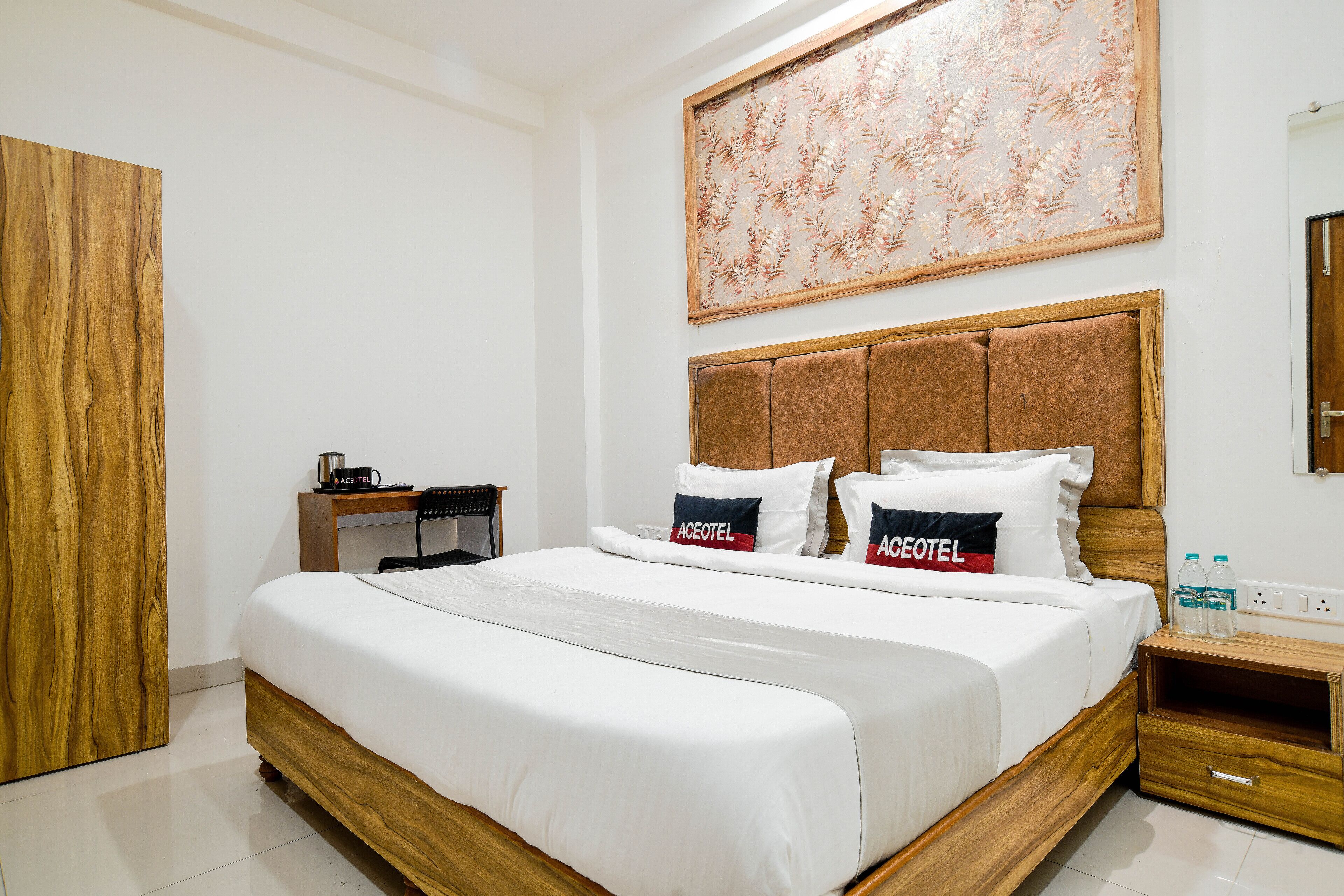 Une chambre d’hôtel avec un lit en bois, un bureau et une grande œuvre d’art florale accrochée au mur.