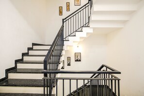 A staircase with black railings and white walls, featuring framed artwork on the walls. - Aceotel Inn Flamingo (Indore)