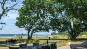 Un patio al aire libre con una mesa y sillas, una silla de descanso y vistas al mar.