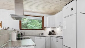 Une cuisine moderne avec des armoires blanches, un comptoir en granit, un four encastré et une fenêtre donnant sur un paysage verdoyant.