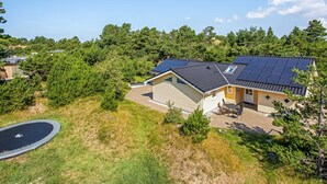 Propiedad residencial con un amplio sistema de paneles solares, un garaje y un césped bien cuidado.