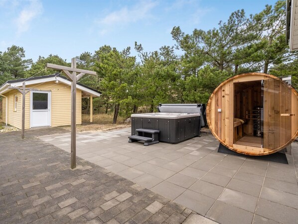 Estructura de sauna de madera con un banco y un jacuzzi en un patio trasero.
