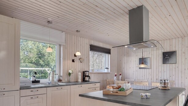 Eine moderne Küche mit Holzvertäfelung, einer zentralen Kochinsel und einem Essbereich.