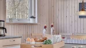 Eine Küche mit Holzvertäfelung, einer Kaffeemaschine, einer Obstschale und einem Fenster mit Blick auf Bäume.
