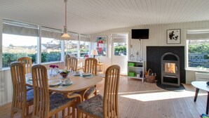Un coin repas avec des chaises et une table en bois, une cheminée et un téléviseur fixé au mur.