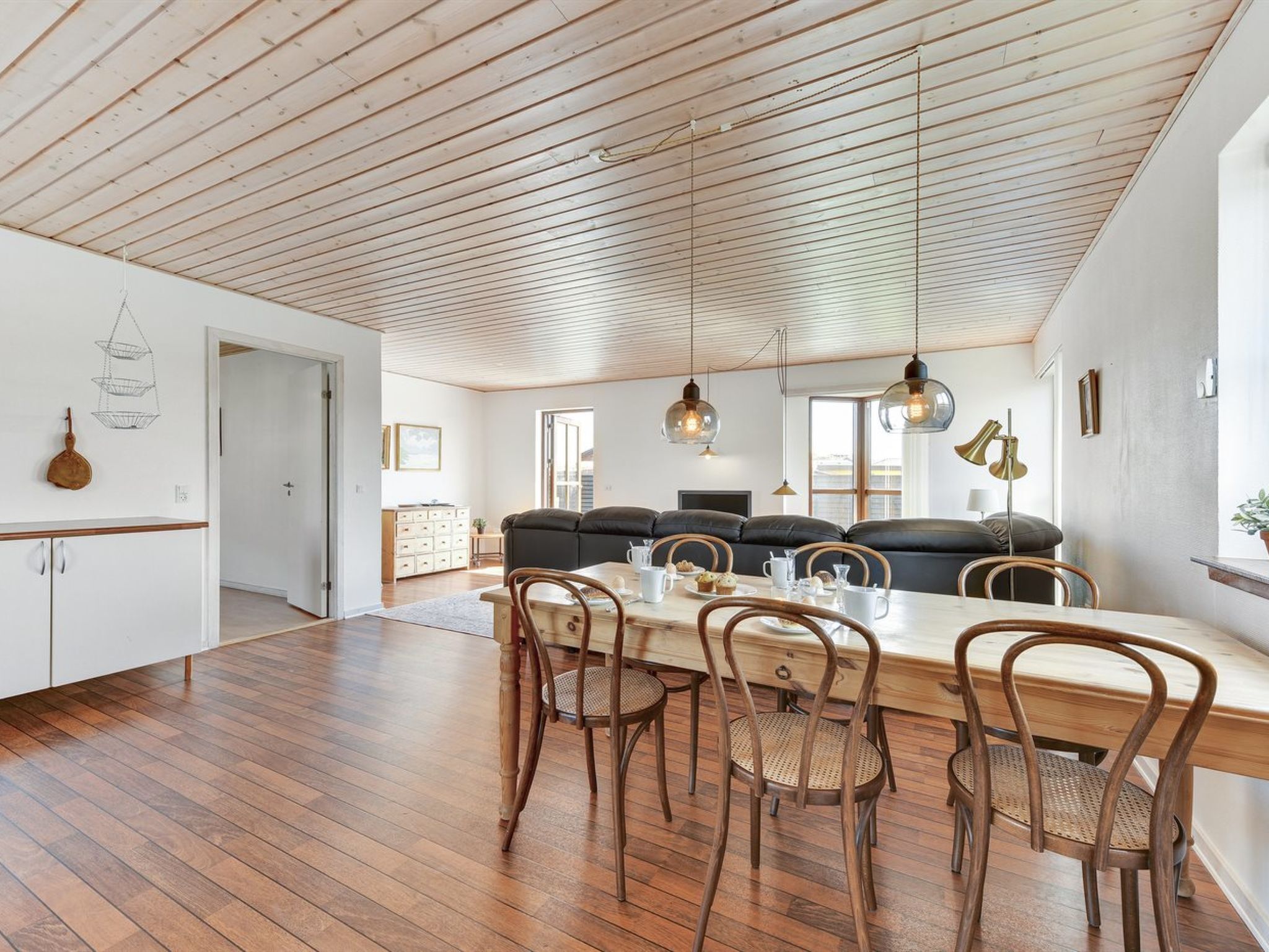 Ein großzügiger Essbereich mit Holztisch und Stühlen, eine hohe Decke mit Holzbalken und eine moderne Küche im Hintergrund.