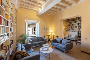 Un salon spacieux avec un plafond haut, des étagères intégrées, un ensemble de canapés, une table basse et une lampe.