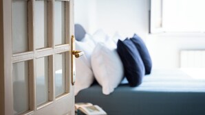 A room with a bed, pillows, a nightstand, and a door.